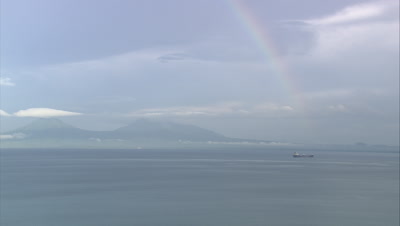 Island in distance with rainbow over it