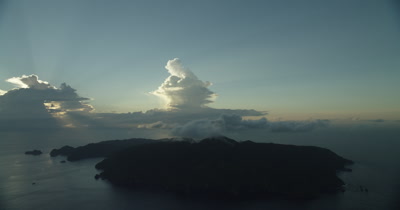 Circling island. Sun peaks through clouds in BG.
