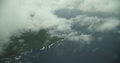 Flying down towards island through clouds