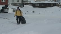 Person Hauls Bag Through Village In Rugged Snowy Area At Base Of Mountain