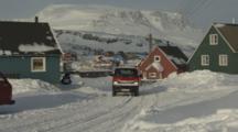 Truck Drives Through Village In Rugged Snowy Area At Base Of Mountain