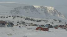 Village In Rugged Snowy Area At Base Of Mountain