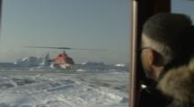 Man Watches Helicopter On Snow Field, From Inside Building