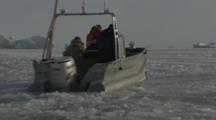 Small Boat Travels Through Melt Ice Toward Icebergs