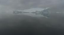 Tilt From Still, Dark Water To Large Iceberg With Reflection
