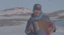 Inuit Man Plays Accordion, Zoom Out To Show Landscape