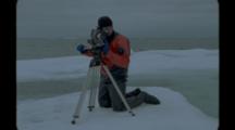 Film Maker In Dry Suit Uses Tripod On Ice