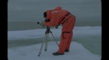 Film Maker In Survival Suit Uses Tripod On Ice