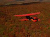 Biplane Flying Over New England In Autumn