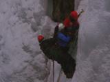 Three People Ice Climbing On Sheer Cliff
