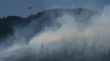 Helicopter Flies Over Forest Fire Carrying Water Bucket