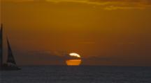 Sailboat Crosses Setting Sun Creating Silhouette In Hawaii