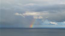 Rainbow Above The Ocean With Cloudy Sky