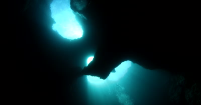 Reveal shot of a Divers in the  Blue Holes Cave, Palau, with light rays, God rays beaming in