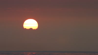 sun breaking thru wide cloud band on horizon