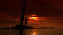 Person Silhouetted On Sailboat Mast At Sunset
