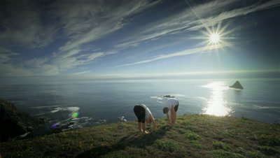 Couple practicing yoga on hillside overlooking Pacific Ocean,OR