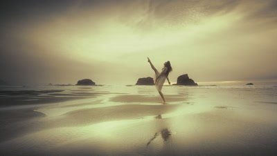 Young woman dancing on beach at sunset Port Orford,OR