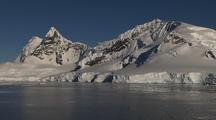Gliding Over Water & Ice Reflecting Antarctic Mountain Shoreline On Mirror Smooth Sea