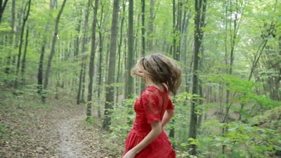 Steadicam shot of a beautiful fairy tale girl in red long dress running in woods