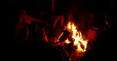 People sitting around of fire in night and talking