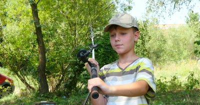 Closeup of a boys hand holding a fishing rod and reel