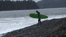 Surfer Walks To Water's Edge.  Remote Rocky Beach