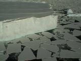 Aerial Shot Of Huge Tabular Iceberg Set In Broken Sea Ice, Antarctica. Helicopter Shadow Provides Some Idea Of Scale.