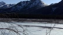 Scenic Snowy Mountain Slow Zoom In To Distant Bear Digging Eating Along Side Snow Ice Covered River