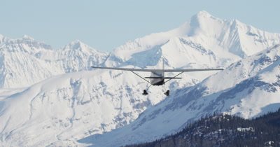 Aerial View of Small Airplane Flying in Alaska Mountains in Winter