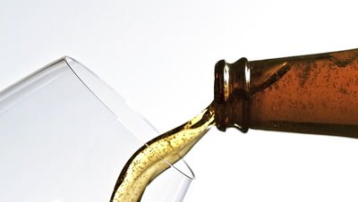 Beer being poured into glass against white background, slow motion