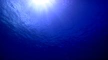 Wide Shot Of The Surface Shot From 30 Feet Below With Sun Burst And Rays, Calm Seas, Blue Sky.
