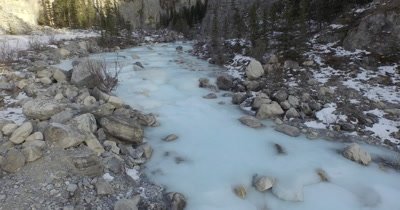 4K Aerial Low level fly over frozen creek in winter Rocky Canyon - NO Colour Correction