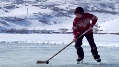 Close up of a boy playing hockey at an outdoor ice rink.