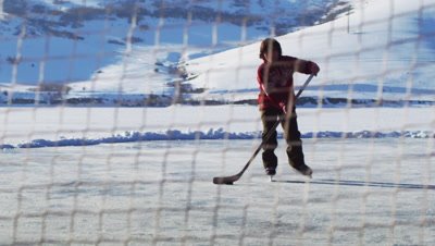 Young boy playing hockey; shoots, slides onto the ice.