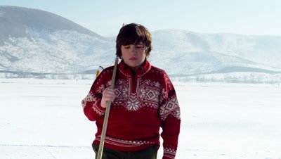 Young boy arriving at a frozen pond to play hockey.