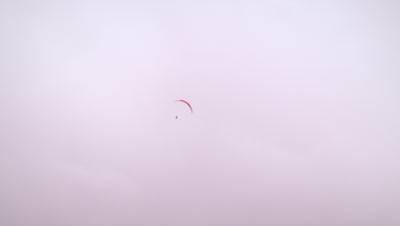 Long distance shot of a lone paraglider spinning in the sky in Switzerland