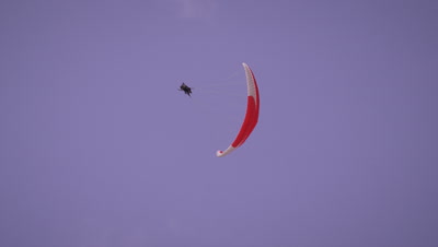 Long distance shot of two people tandem paragliding dangerously spinning in the sky