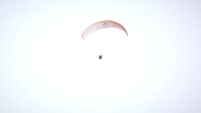 Long distance static shot of two people tandem paragliding in Switzerland