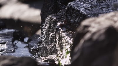Close-up slow motion shot of water cascading over rocks.