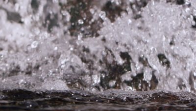 Slow motion closeup of water crashing at the bottom of a waterfall.