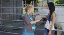 Women Stand Talking Near Livestock Corral