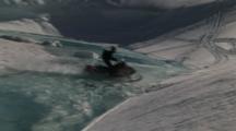 A Snowmobiler Rides Over Water And Into A Bowl And One Crashes And Almost Loses His Sled.