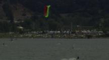 Many Kiteboarders And Windsurfers In The Water And On Shore.