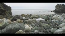 Colorful Rocks Fill The Shoreline Of A Coastal Beach, Calm Seas And Gulls Are In The Frame, Big Sur. Cine-Slider Shot.