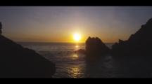 Time Lapse Of Waves Coming Ashore Along A Dark Rocky Coast, With A Golden Ocean. Shot Goes From Golden To Dark.