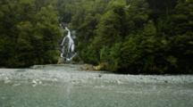 Waterfall Streaming Through Rainforest, With Rocky Riverbed In Foreground. Pan From Top To Base. South Island, New Zealand.