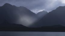 Lake Manapouri At Dusk With Dramatic Light On The Water And Mountains.