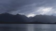 Lake Manapouri At Dusk With Thick Clouds And Dramatic Light On The Water And Mountains.