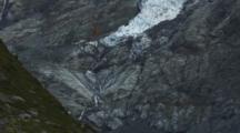 Glaciers Cling To The Steep Mountains Of The Southern Alps. Water Flows From The Base Of The Glacier.